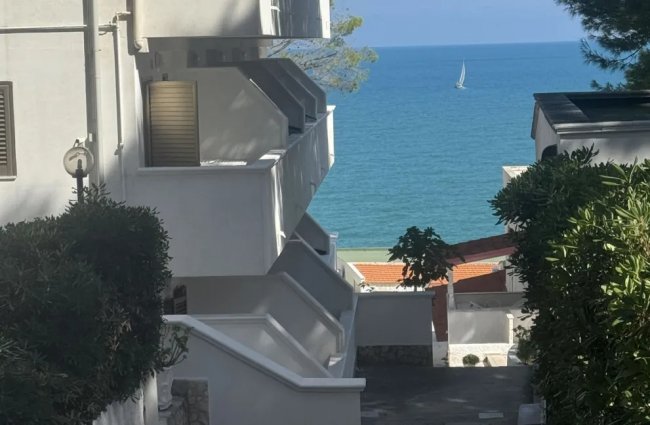 Edifici bianchi con vista sul mare e barca a vela.