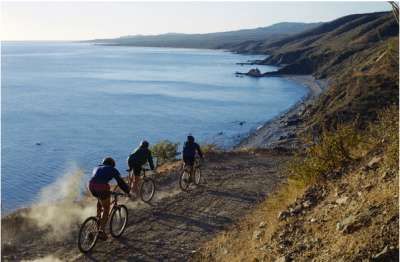 Tre ciclisti su un sentiero polveroso lungo la costa.