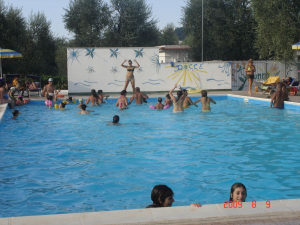 Persone che nuotano e si divertono in una piscina all'aperto con un murales.