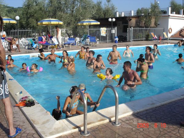 Persone che si divertono in una piscina all'aperto, circondati da ombrelloni gialli.