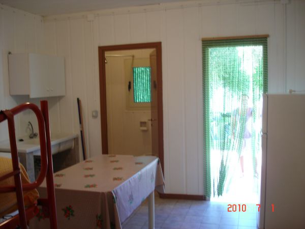 Stanza semplice con tavolo coperto e accesso esterno.