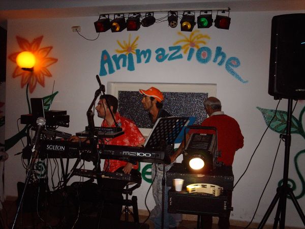 Musicisti suonano strumenti all'interno di una sala con la scritta 