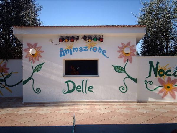 Un piccolo edificio bianco con murales di fiori e la scritta 