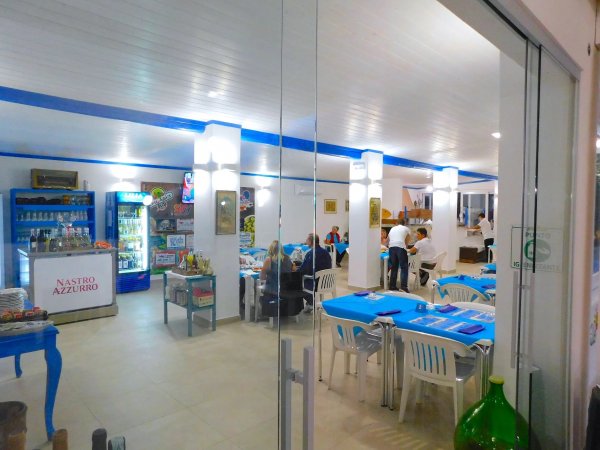 Ristorante interno con tavoli blu e sedie bianche.