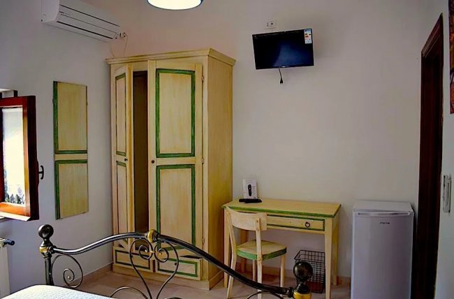 Camera con armadio, scrivania e televisore.