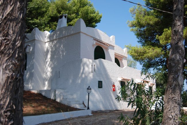 Casa bianca con terrazza in mezzo agli alberi.
