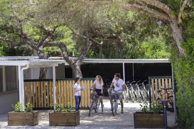 Persone con biciclette vicino a un edificio di legno.