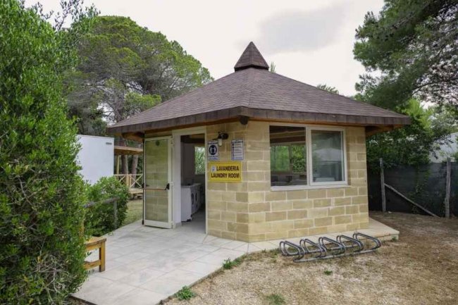 Un edificio lavanderia in pietra con tetto a punta, tra gli alberi.