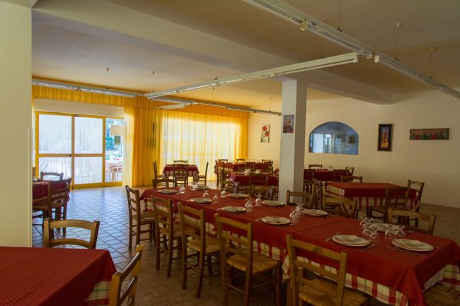 Interno di ristorante con tendaggio giallo e tavoli apparecchiati.