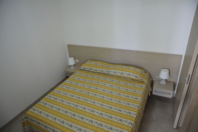 Letto matrimoniale con copriletto a righe gialle.