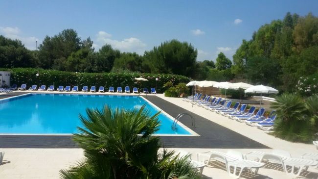 Piscina circondata da lettini e ombrelloni.