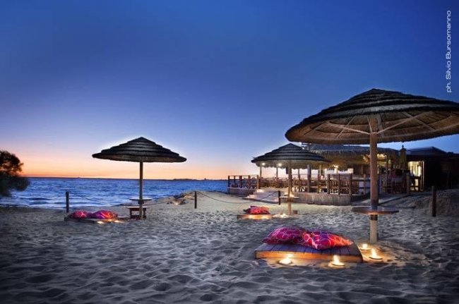 Spiaggia con ombrelloni al tramonto.