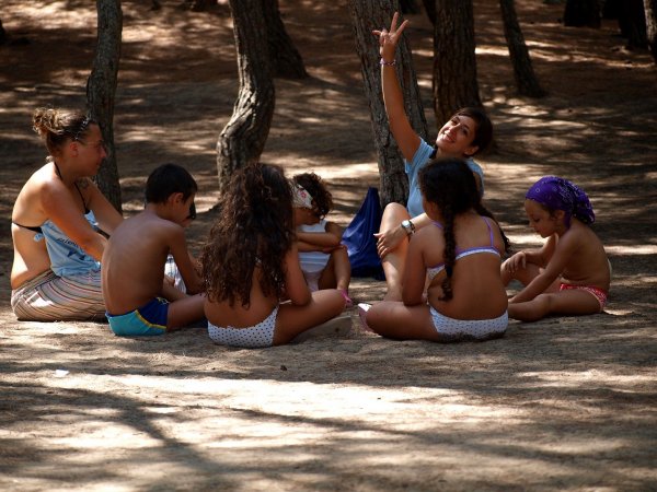 Gruppo di bambini seduti in cerchio nel bosco.