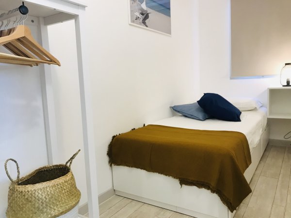 Camera moderna con letto singolo, cuscini colorati.