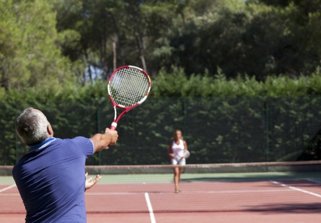 Partita di tennis tra due persone su campo all'aperto.