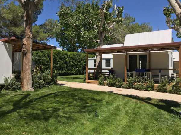 Bungalow moderno con giardino verde e alberi.