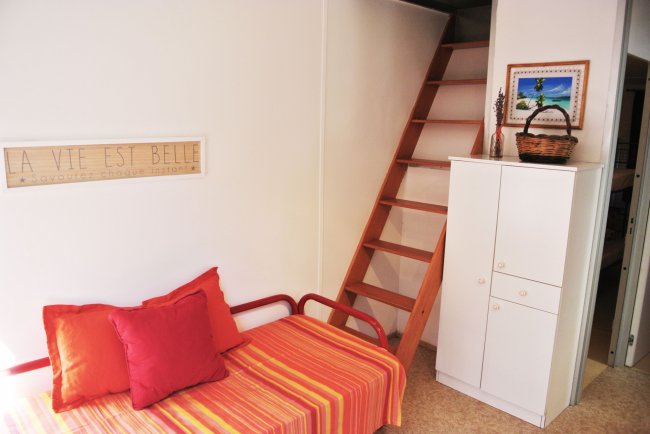 Divano rosso e scala a pioli, arredo semplice e colorato.