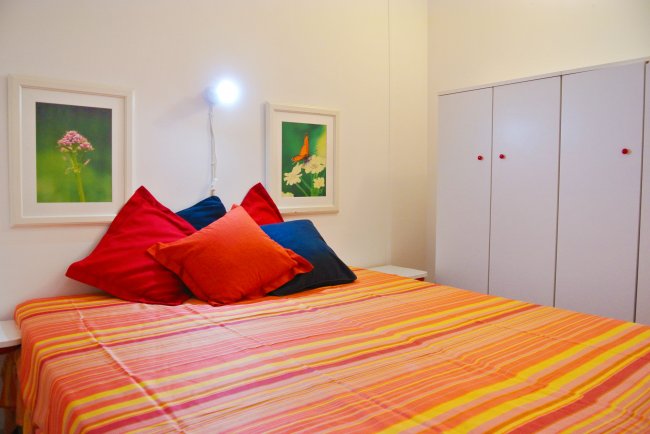 Letto colorato con cuscini e quadri.