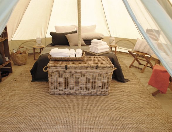 Interno di tenda con letto e cesta di vimini.
