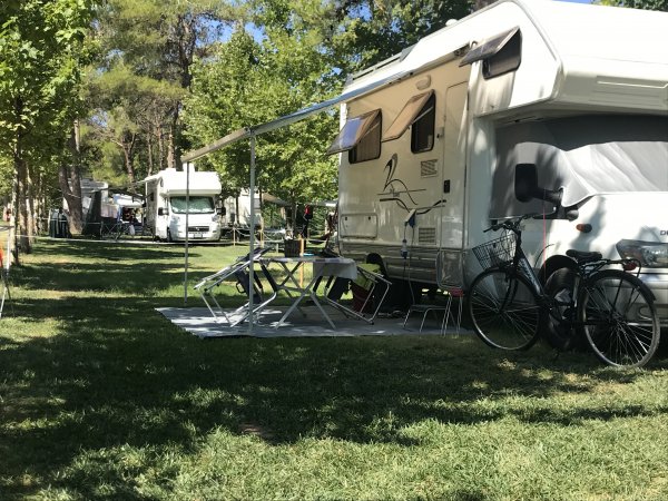 Camper parcheggiato con biciclette e sedie.