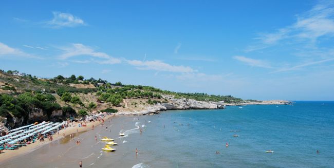 Spiaggia con pedalò gialli e mare blu limpido.