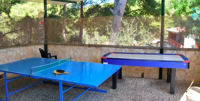 Un tavolo da ping pong blu accanto a un tavolo da air hockey in un'area esterna coperta.
