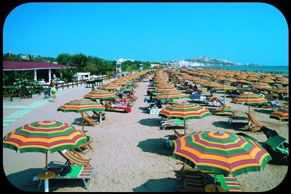 Spiaggia affollata con ombrelloni colorati.