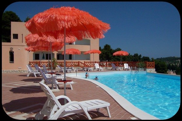 Piscina con lettini e ombrelloni arancioni.