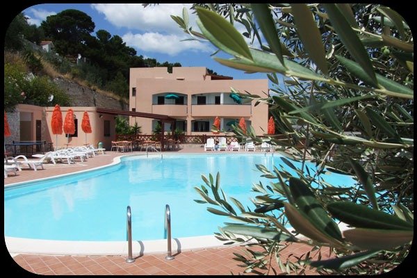 Piscina scoperta con edifici e ombrelloni arancioni.