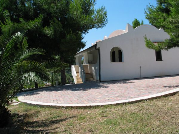 Casa bianca tra alberi e sentiero piastronato.