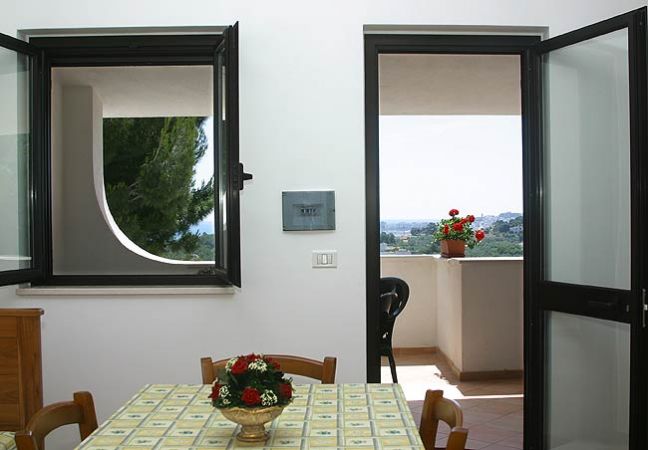 Interno con tavolo fiorito e vista su balcone.