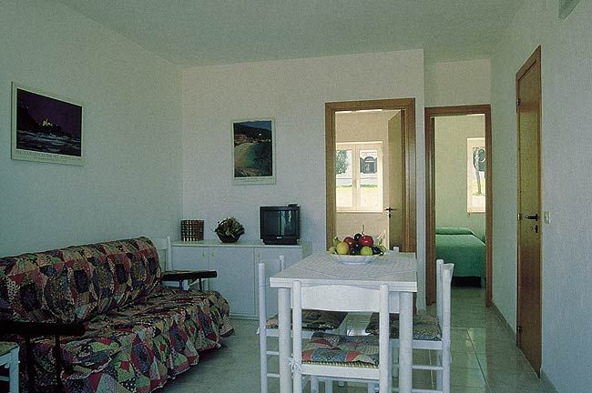 Interno di una stanza con tavolo, divano e televisore.