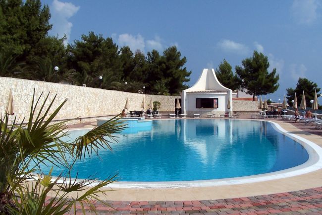 Una piscina circondata da lettini e ombrelloni.
