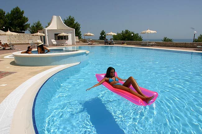 Donna su materassino rosa in piscina all'aperto.