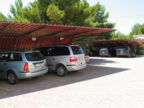 Parcheggio coperto con auto parcheggiate sotto tettoie rosse.