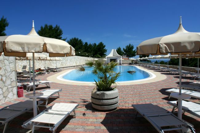 Piscina circondata da lettini e ombrelloni bianchi.