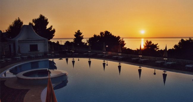 Piscina al tramonto con vista sul mare.