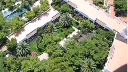 Vista dall'alto di edifici bianchi circondati da rigogliosi alberi e palme.