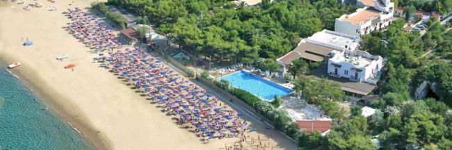 Spiaggia con ombrelloni colorati e un'area alberata con piscina.