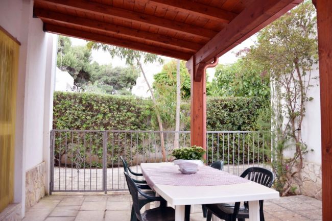 Tavolo con sedie sotto un portico in giardino.