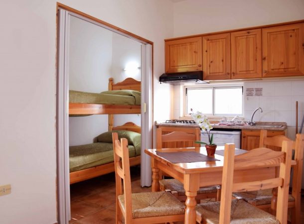Cucina con tavolo in legno, letti a castello adiacenti.