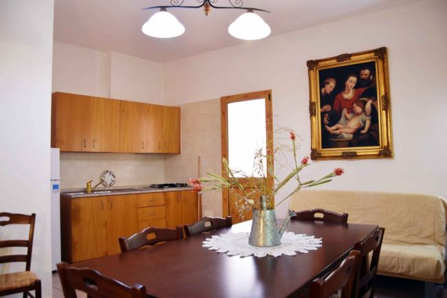 Sala da pranzo con tavolo in legno e dipinto su parete.