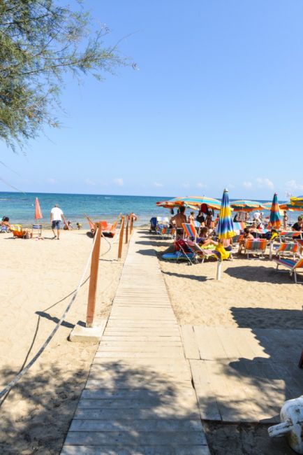 Spiaggia con ombrelloni colorati e passerella.
