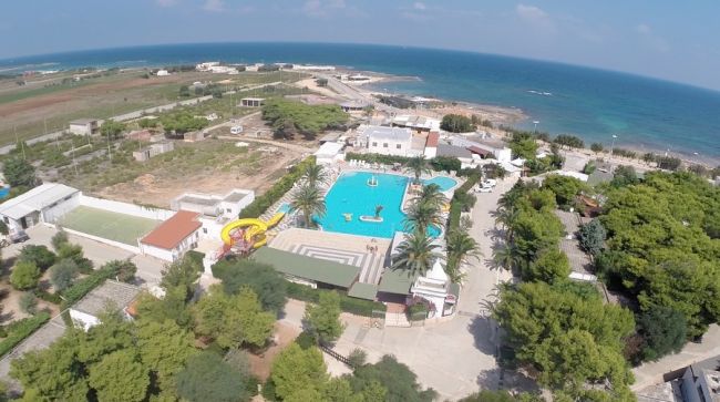 Vista aerea di un complesso con piscina vicino al mare.