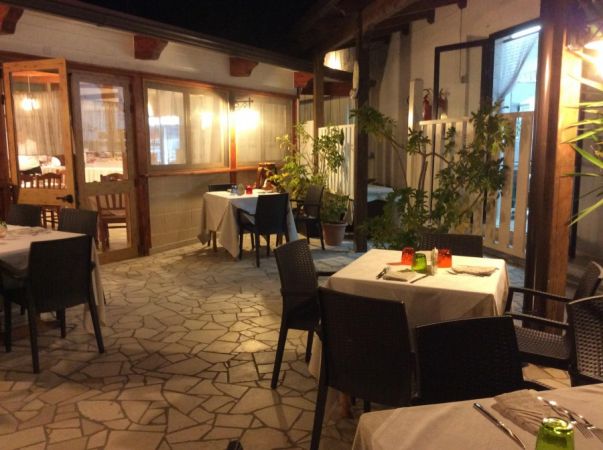 Un patio esterno con tavoli apparecchiati e sedie intorno.