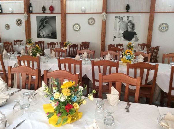 Una sala da pranzo con tavoli allestiti e fiori, foto alle pareti.