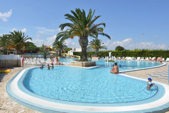 Piscina con palme e persone in acqua.