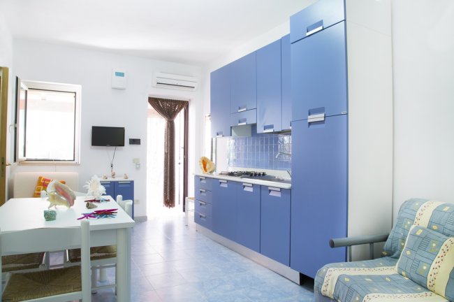 Cucina azzurra moderna con tavolo bianco.
