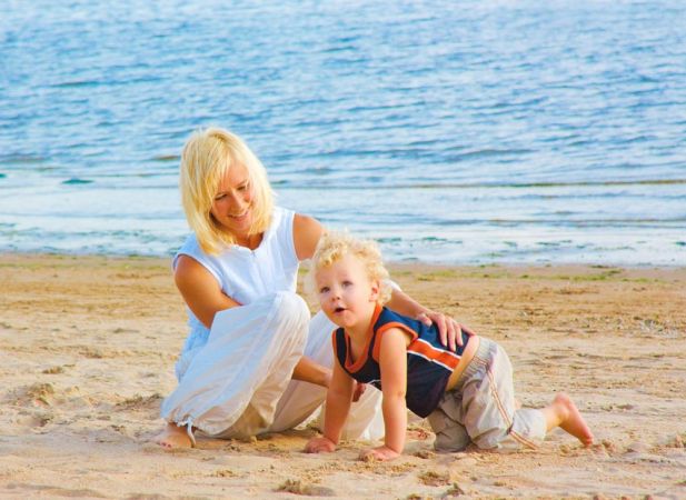 Una donna e un bambino giocano sulla spiaggia vicino al mare.