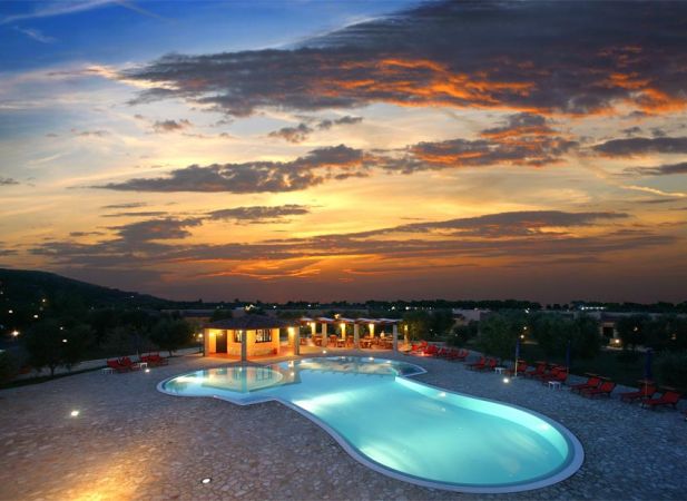 Una piscina illuminata al tramonto con cielo arancione e rosso.